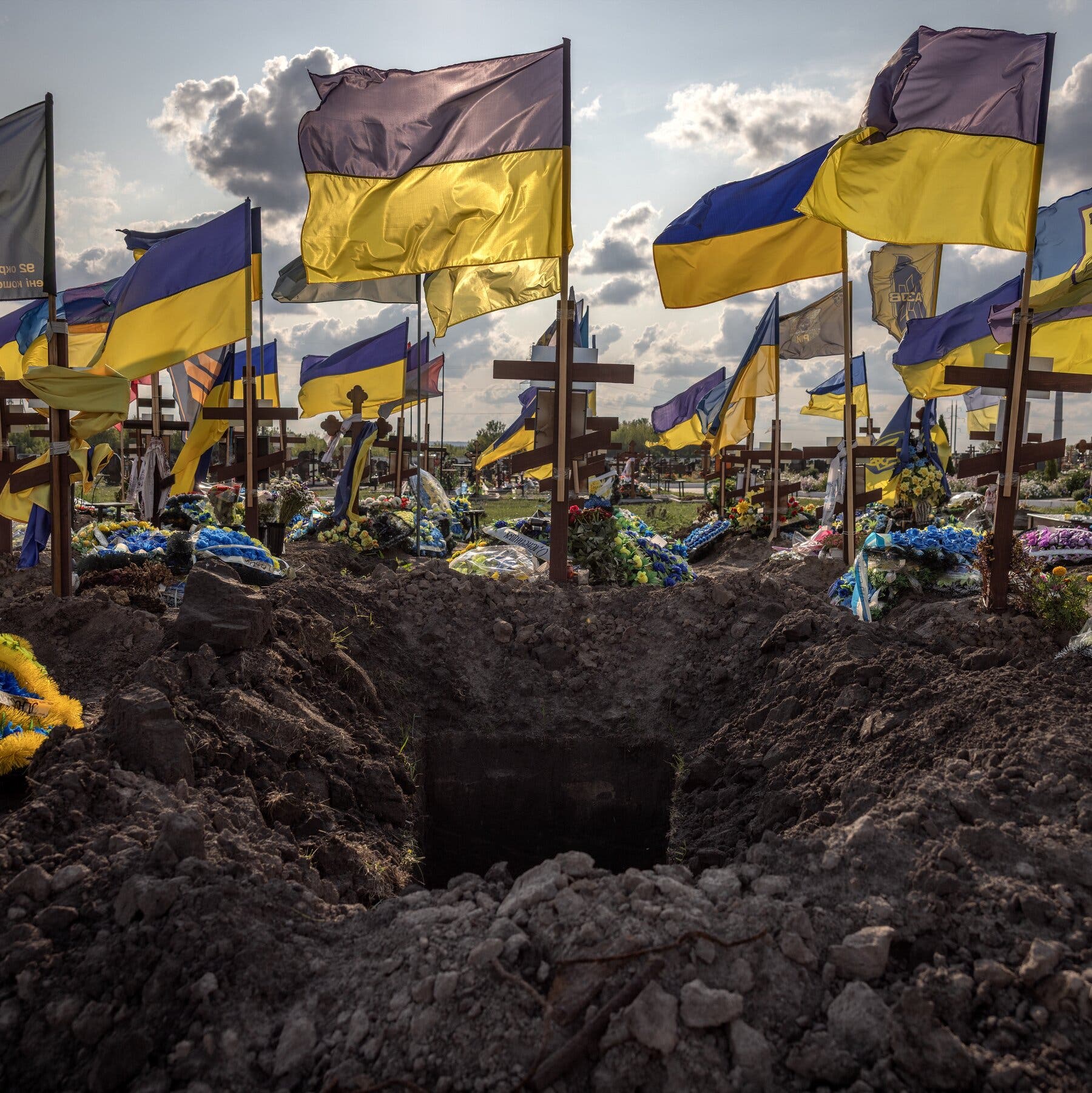 2026-01-05 ¡25mag-ai-drones-homepage-mobileMasterAt3x.jpg|A freshly dug grave in the foreground of a cemetery covered with flowers and blue-and-yellow Ukrainian flags. 