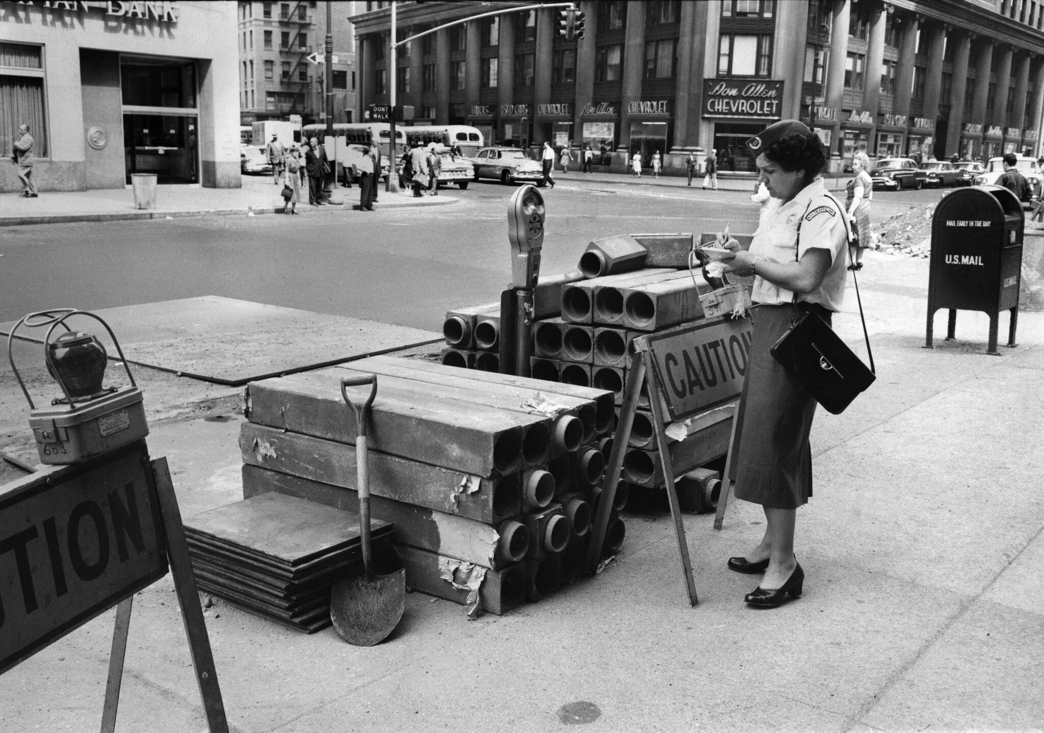 2026-06-10 ¡00met-parking-timeline-meter-gjwc-superJumbo.jpgA woman writes something while standing next to a parking meter that is surrounded by construction materials.