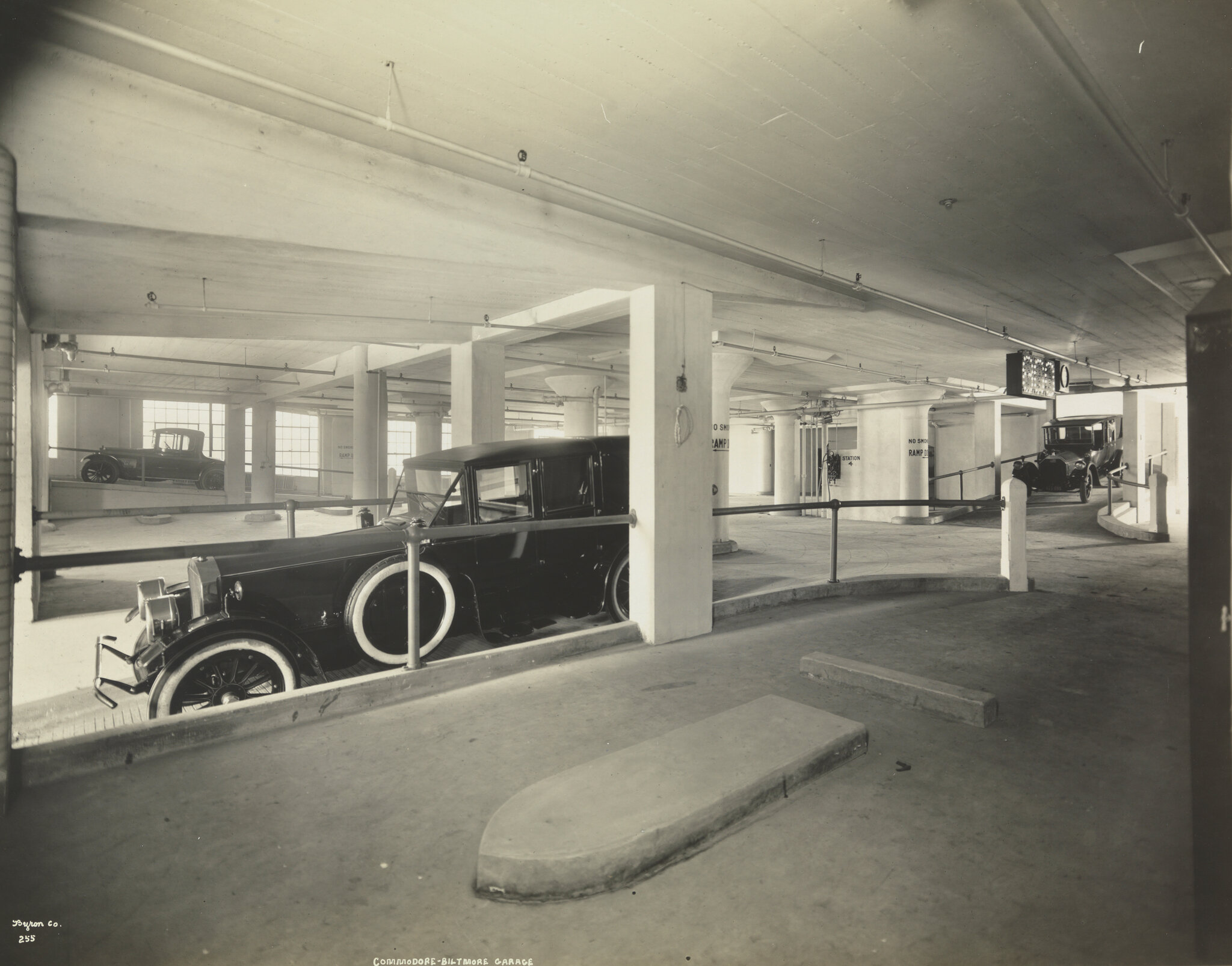 2026-06-10 ¡parking-timeline-02-fgwb-superJumbo-v2.jpgA black-and-white photo from 1919 of a large covered parking lot with several cars in it.
