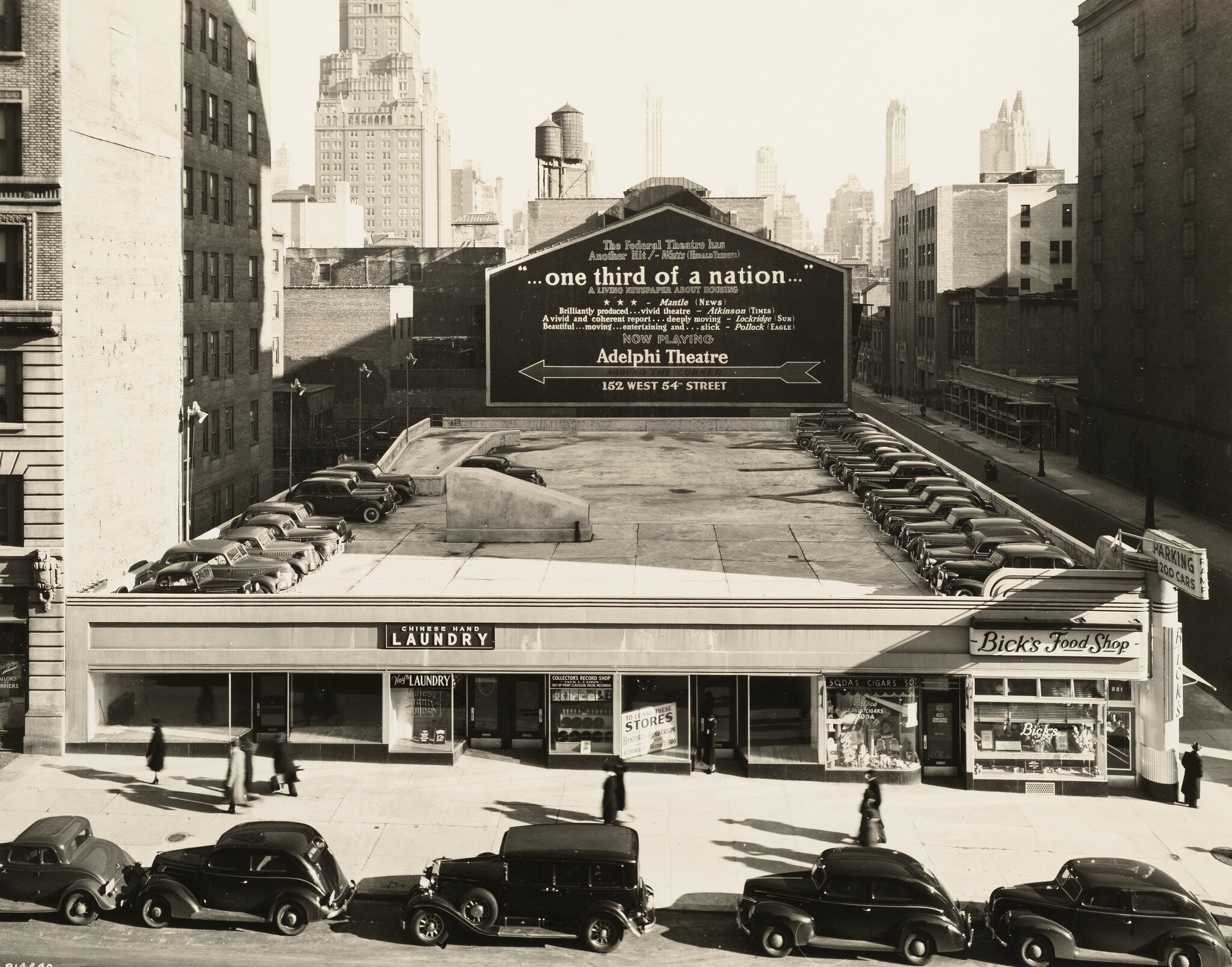 2026-06-10 ¡parking-timeline-06-fgwb-superJumbo-v2.jpgA 1930s photo of cars parked in front of a one-story building that has a parking deck on the roof.
